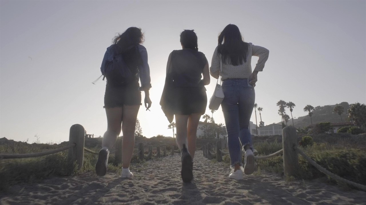 Three woman walking down a beach path