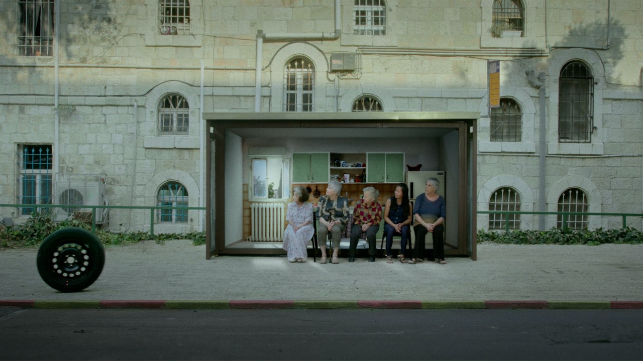 A group of people sit in front of a small model ki