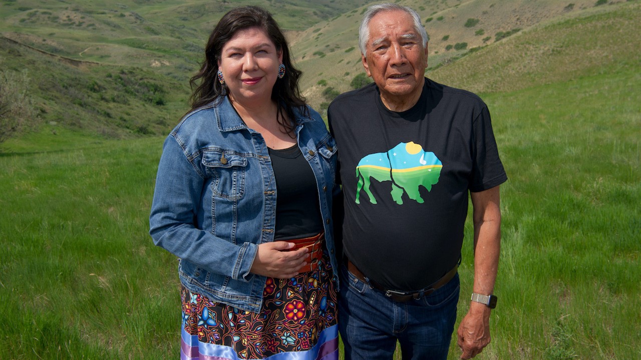 Woman and man stand in a grass field