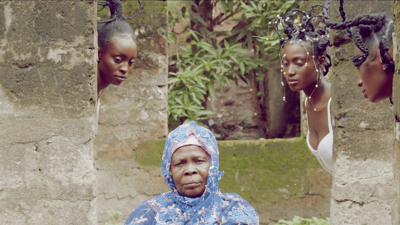 An old woman with 3 young woman surrounding her