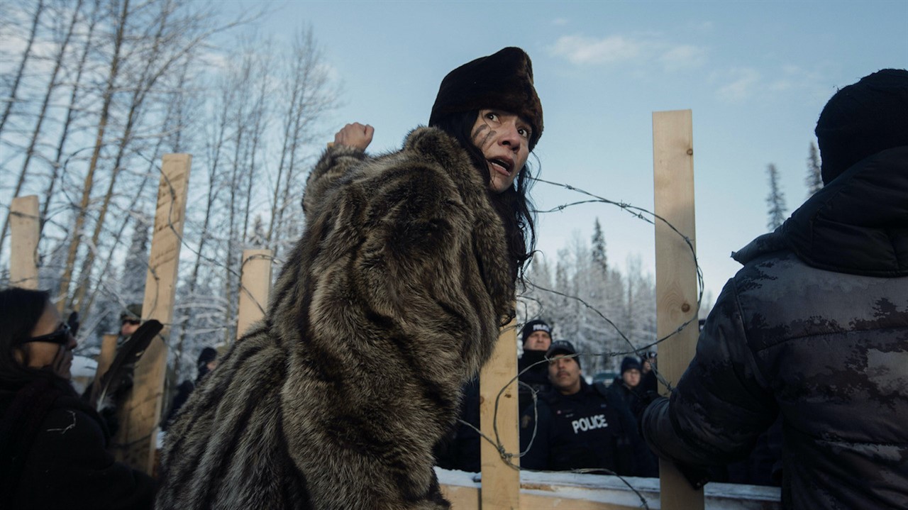 Protestor in fron of a barbed wire blockade