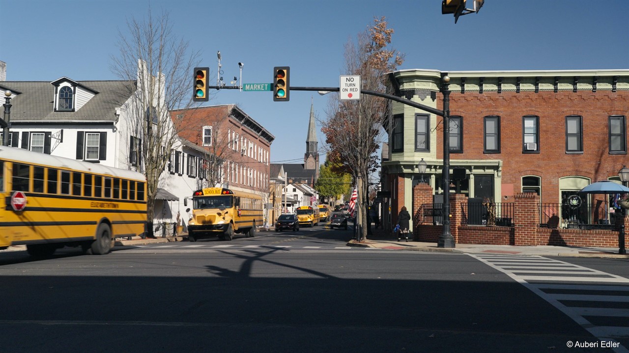 School buses drive down a small town road.