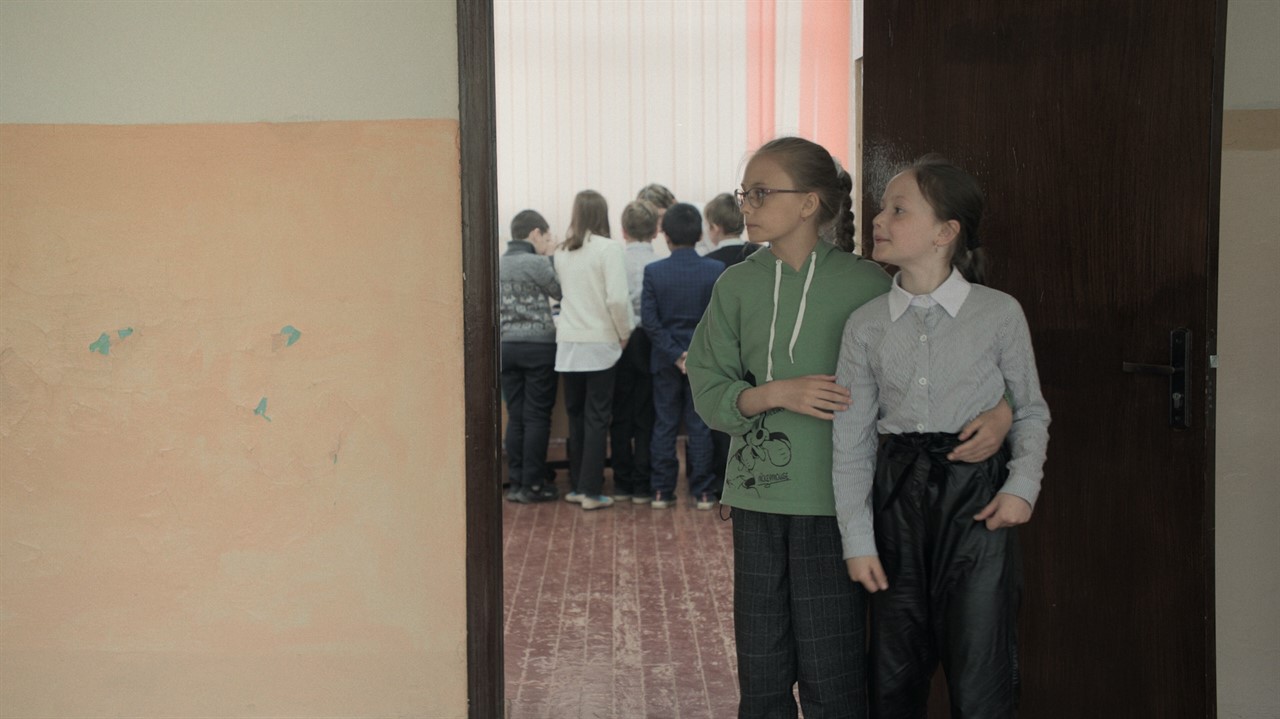 Two young girls stand in a doorway