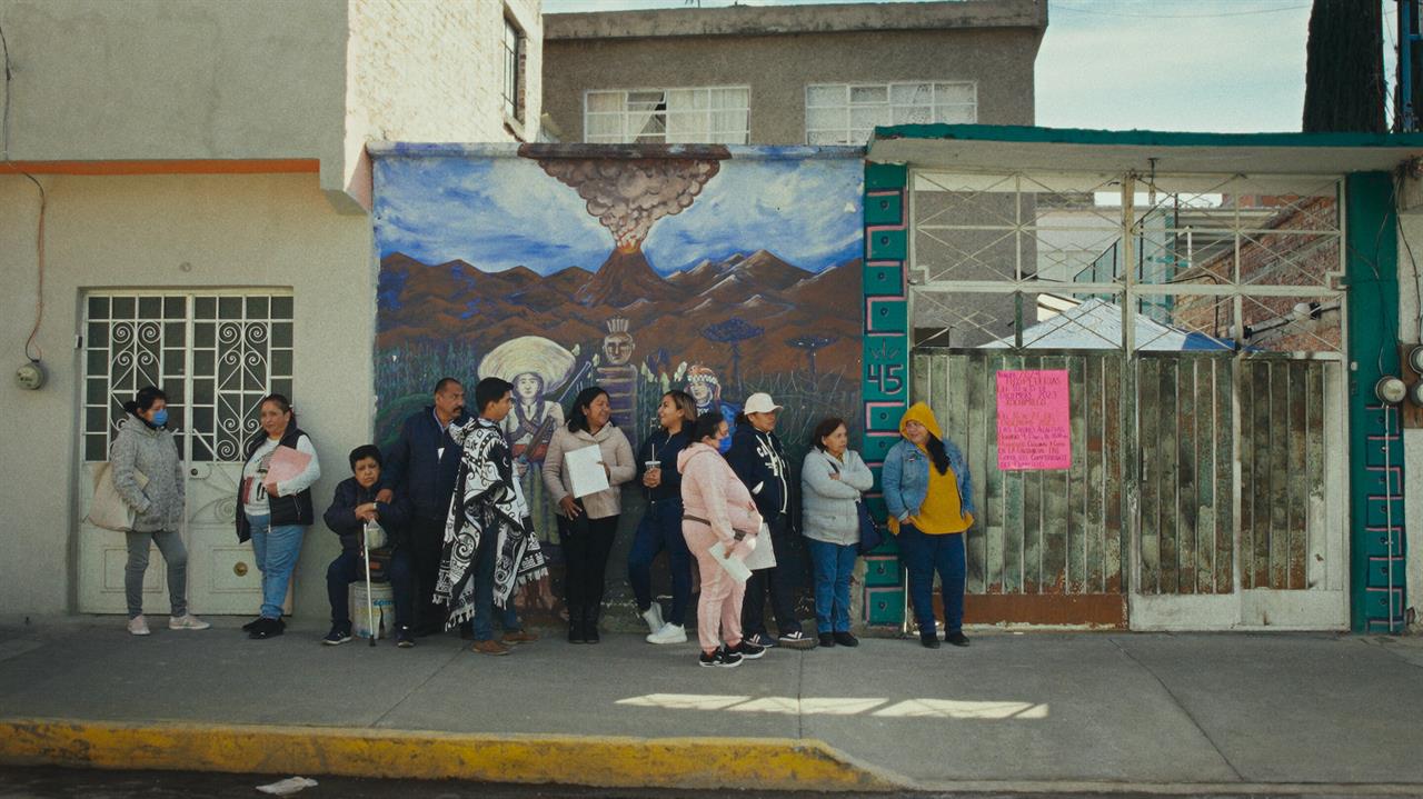 People wait in line against a wall 
