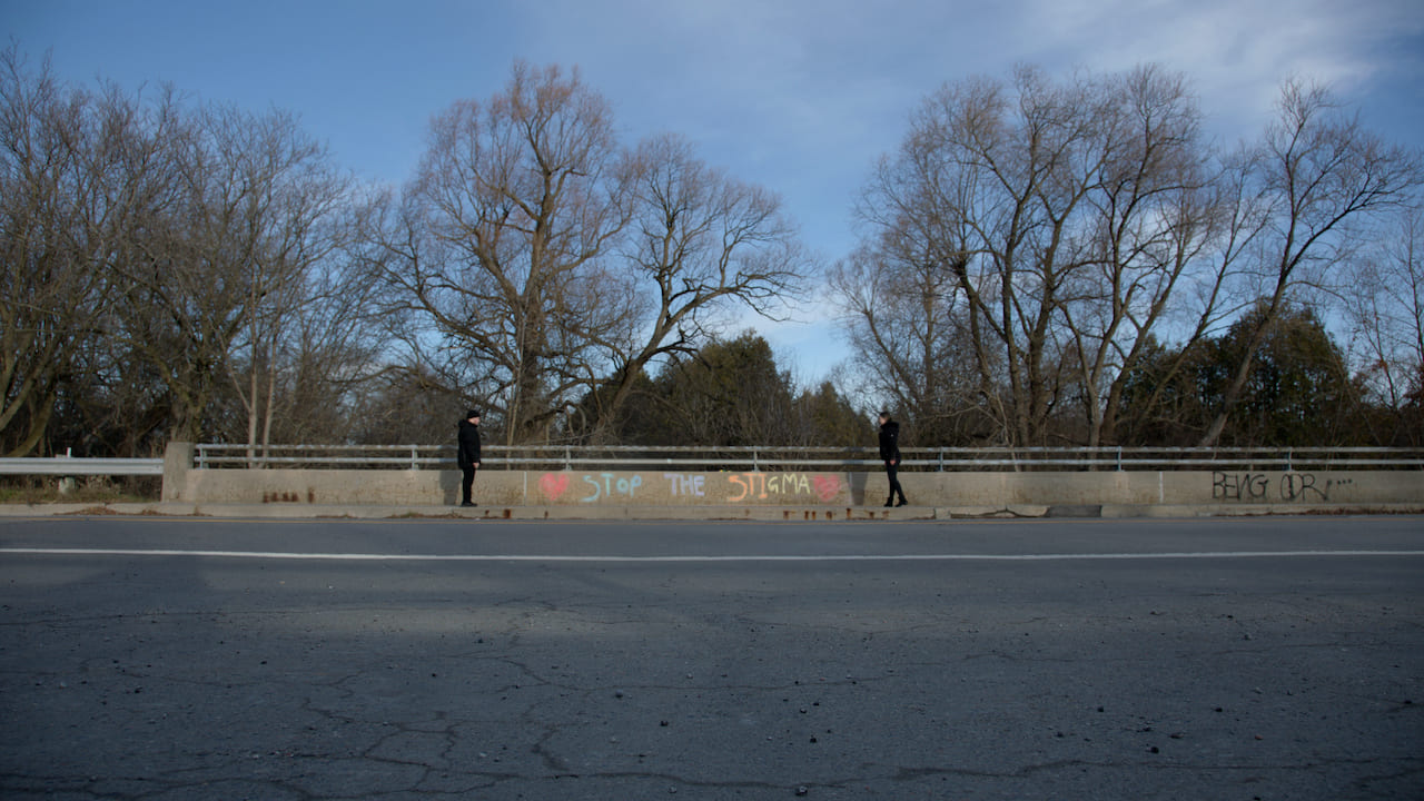 Two people stand on a city bridge