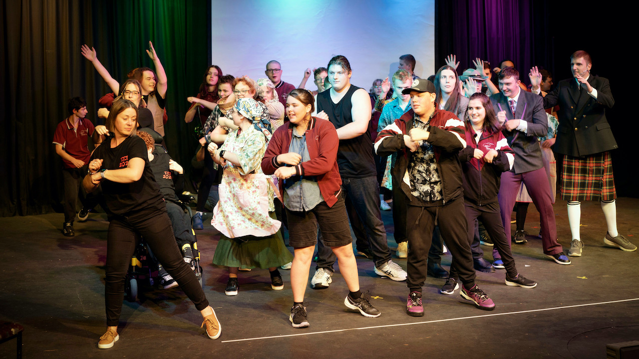 Group of teens rehersing a dance on stage